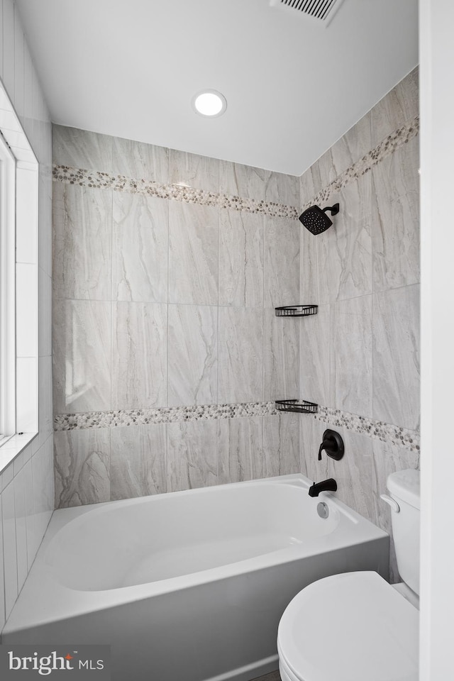 bathroom with shower / bathtub combination, toilet, and tile walls