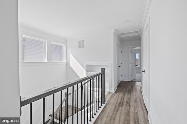 corridor featuring wood finished floors, visible vents, baseboards, crown molding, and an upstairs landing