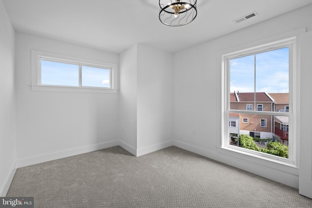 spare room featuring visible vents, carpet flooring, baseboards, and an inviting chandelier