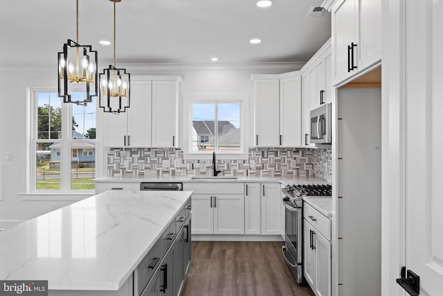 kitchen with white cabinets, sink, hanging light fixtures, light stone counters, and stainless steel appliances