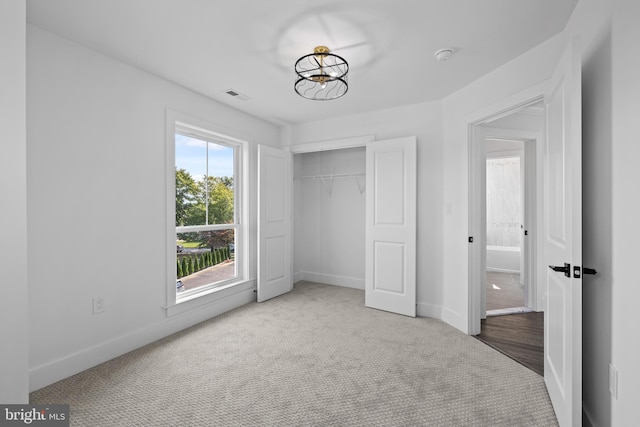 unfurnished bedroom featuring a chandelier, visible vents, carpet, and baseboards