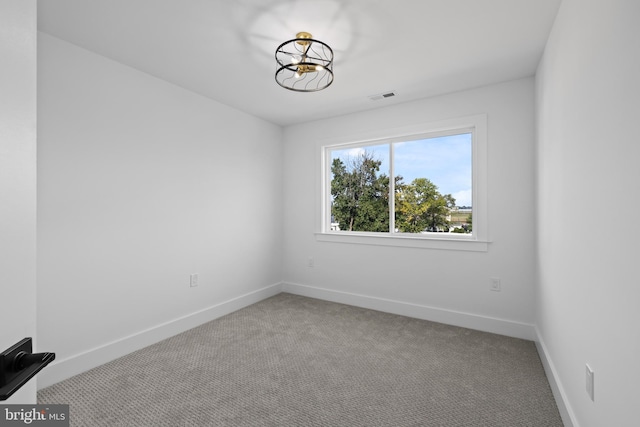 empty room featuring carpet flooring, baseboards, visible vents, and a chandelier