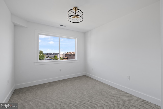 spare room featuring visible vents, carpet, and baseboards