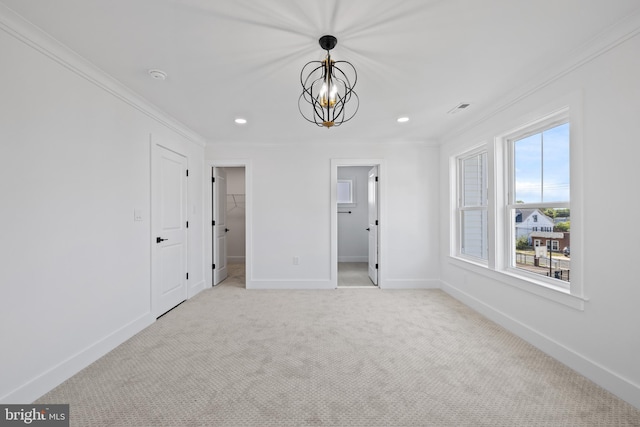 unfurnished bedroom with a notable chandelier, carpet, crown molding, baseboards, and a spacious closet