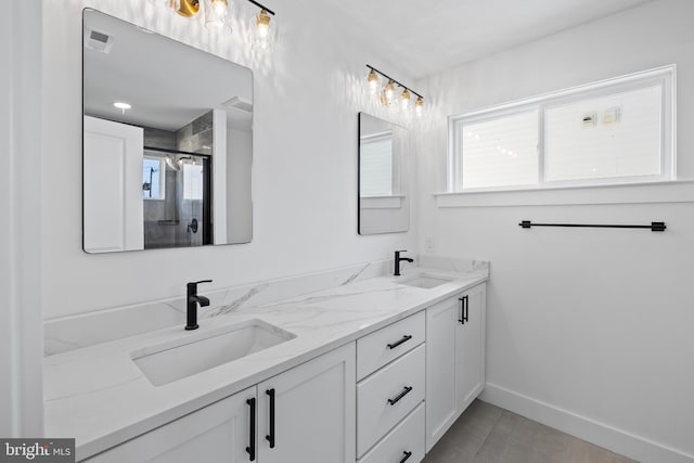 full bathroom featuring double vanity, a shower stall, baseboards, and a sink