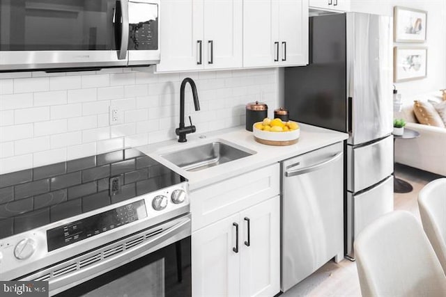 kitchen featuring tasteful backsplash, white cabinetry, sink, and stainless steel appliances