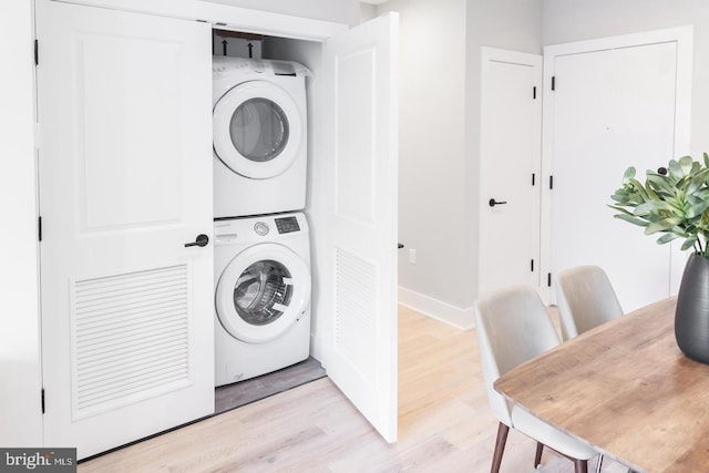 laundry area with light hardwood / wood-style floors and stacked washer and dryer