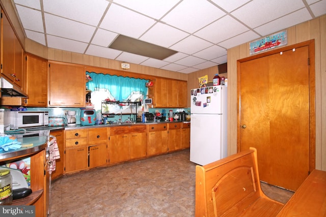 kitchen featuring wood walls, sink, and white appliances