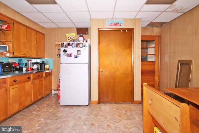 kitchen featuring wooden walls and white fridge