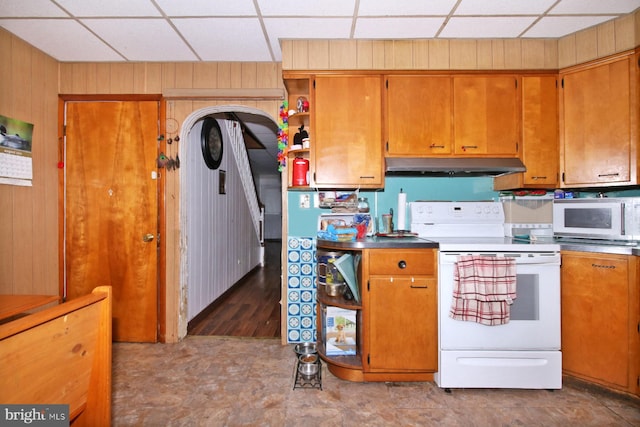 kitchen featuring white appliances, a drop ceiling, and wooden walls