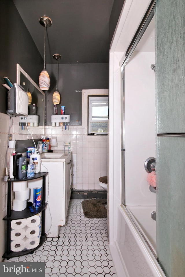 bathroom with tile patterned floors, vanity, bath / shower combo with glass door, and tile walls