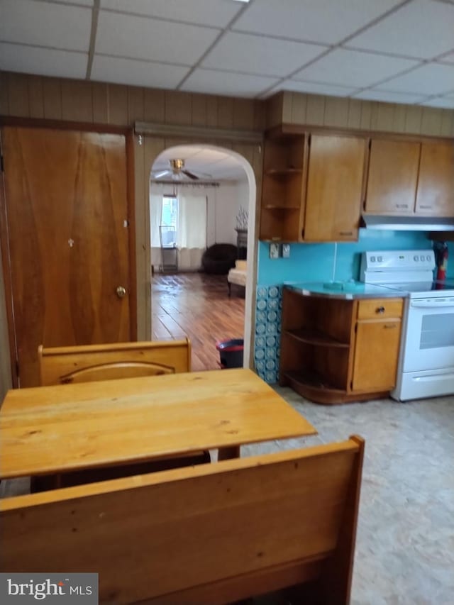 kitchen with electric stove, a paneled ceiling, and wooden walls