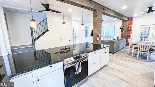 kitchen featuring light wood-type flooring, stainless steel electric stove, dark stone countertops, white cabinetry, and hanging light fixtures