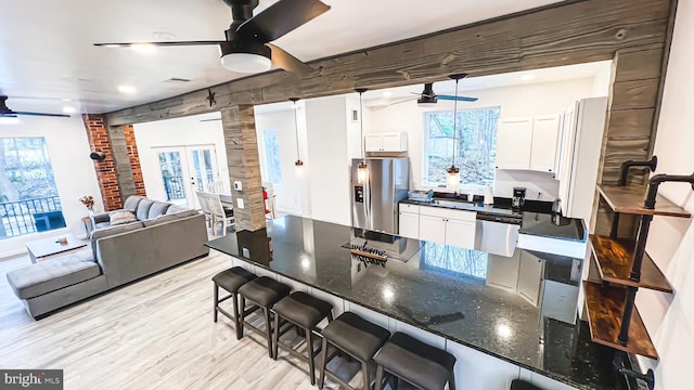 kitchen with ceiling fan, dark stone countertops, a breakfast bar area, white cabinets, and appliances with stainless steel finishes