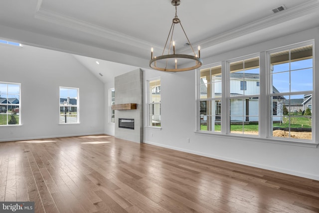 unfurnished living room with hardwood / wood-style floors, a notable chandelier, a large fireplace, and a tray ceiling