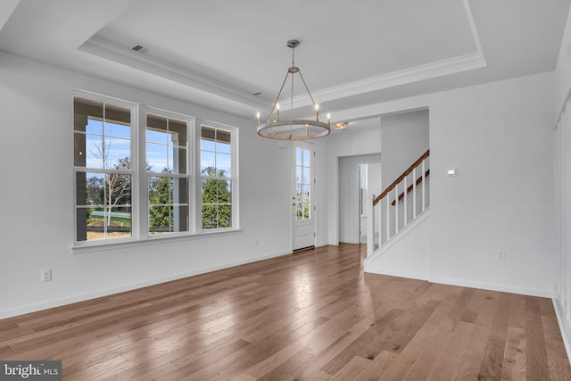 foyer with a notable chandelier, wood-type flooring, and a tray ceiling