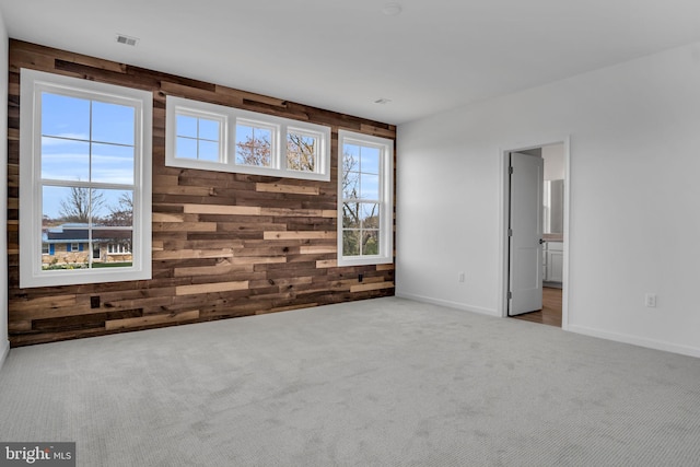 carpeted spare room featuring wooden walls