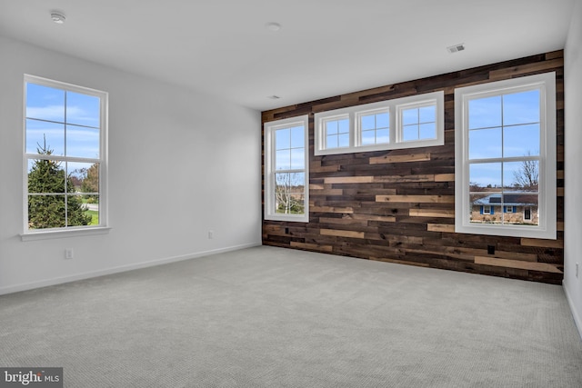 carpeted spare room featuring wood walls