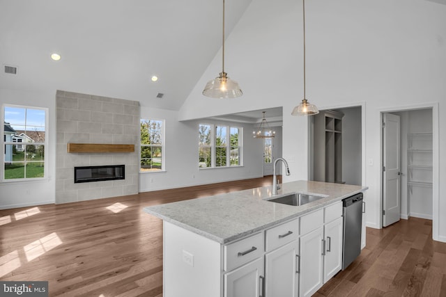 kitchen featuring white cabinetry, sink, dishwasher, a fireplace, and a center island with sink