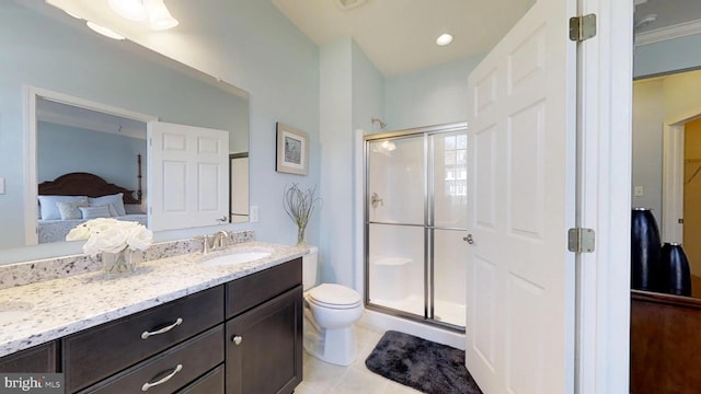 bathroom featuring tile patterned floors, vanity, a shower with shower door, and toilet