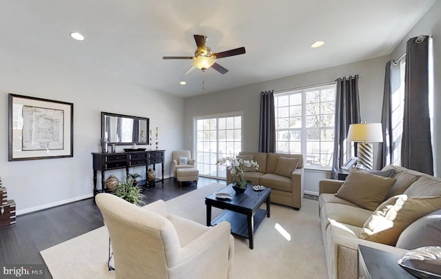 living room featuring ceiling fan, plenty of natural light, and dark wood-type flooring