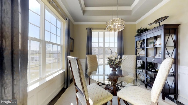 dining space with an inviting chandelier, ornamental molding, and a tray ceiling