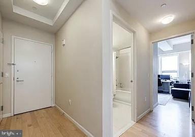 hallway featuring light hardwood / wood-style floors and a tray ceiling