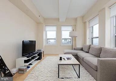 living room with beam ceiling, light hardwood / wood-style flooring, and a healthy amount of sunlight