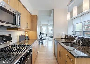 kitchen featuring appliances with stainless steel finishes, backsplash, sink, dark stone countertops, and hanging light fixtures