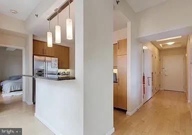 kitchen with stainless steel fridge, decorative light fixtures, and light wood-type flooring