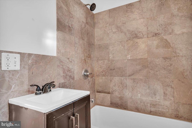 bathroom featuring tile walls, vanity, and tiled shower / bath