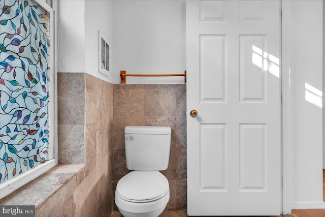 bathroom featuring tile walls and toilet