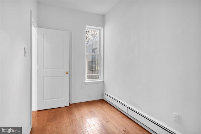 unfurnished room featuring light hardwood / wood-style floors and a baseboard radiator