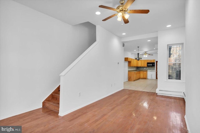 unfurnished living room featuring ceiling fan and light hardwood / wood-style floors