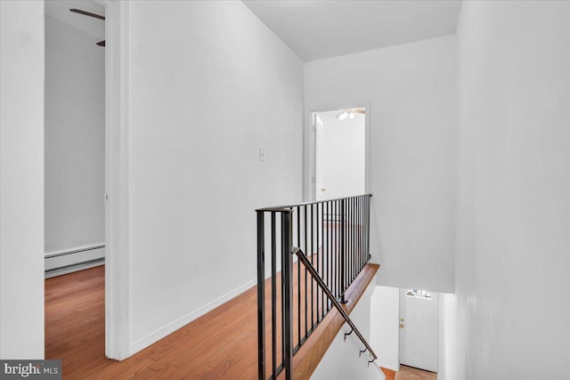 corridor with a baseboard radiator and light hardwood / wood-style flooring