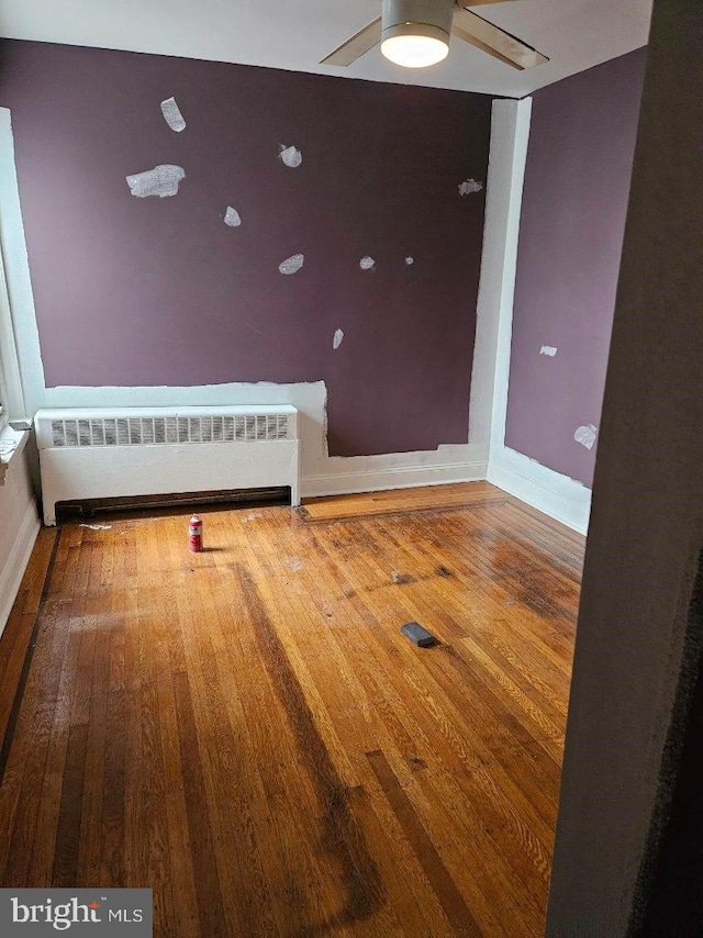 spare room with wood-type flooring, radiator, and ceiling fan