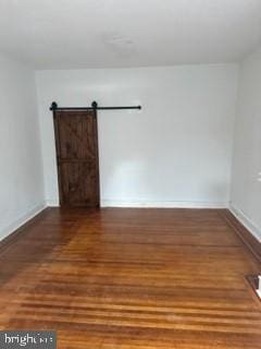 empty room featuring dark hardwood / wood-style flooring and a barn door