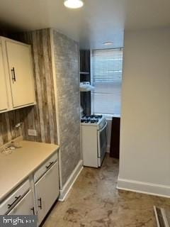 kitchen featuring white cabinets, ventilation hood, and white gas range