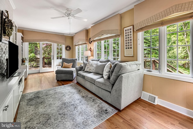 living area with ceiling fan, visible vents, crown molding, baseboards, and light wood-style flooring