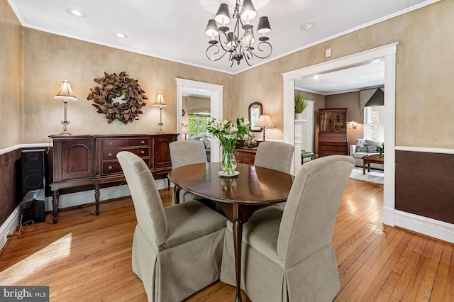 dining area with an inviting chandelier, light wood finished floors, crown molding, and a healthy amount of sunlight