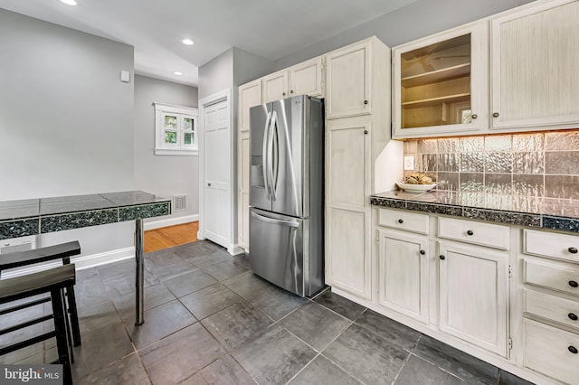 kitchen with stainless steel fridge, glass insert cabinets, tasteful backsplash, and recessed lighting