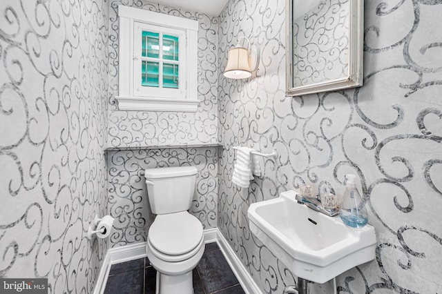 bathroom featuring a sink, baseboards, and wallpapered walls