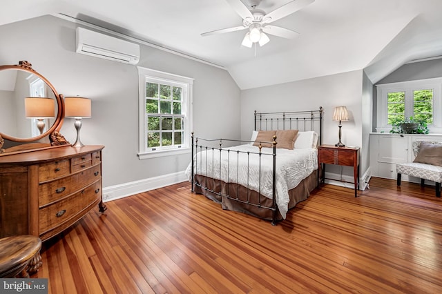 bedroom with baseboards, vaulted ceiling, a wall unit AC, and hardwood / wood-style flooring