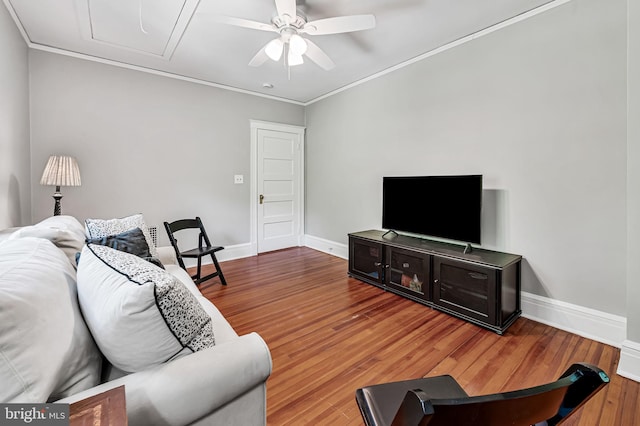 living area featuring ceiling fan, ornamental molding, baseboards, and wood finished floors