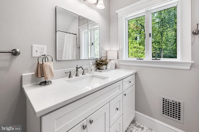full bath featuring vanity, baseboards, and visible vents