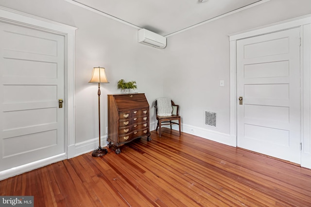 living area featuring baseboards, a wall mounted AC, wood finished floors, and visible vents