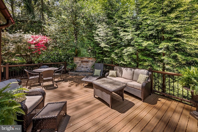 wooden terrace with an outdoor living space, a wooded view, and outdoor dining space