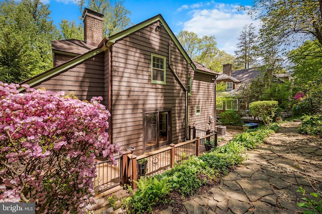 view of side of home featuring a chimney and a deck