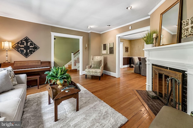 living room featuring crown molding, stairway, a fireplace with flush hearth, and hardwood / wood-style flooring