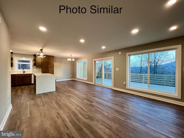 unfurnished living room with dark hardwood / wood-style floors, a notable chandelier, and sink